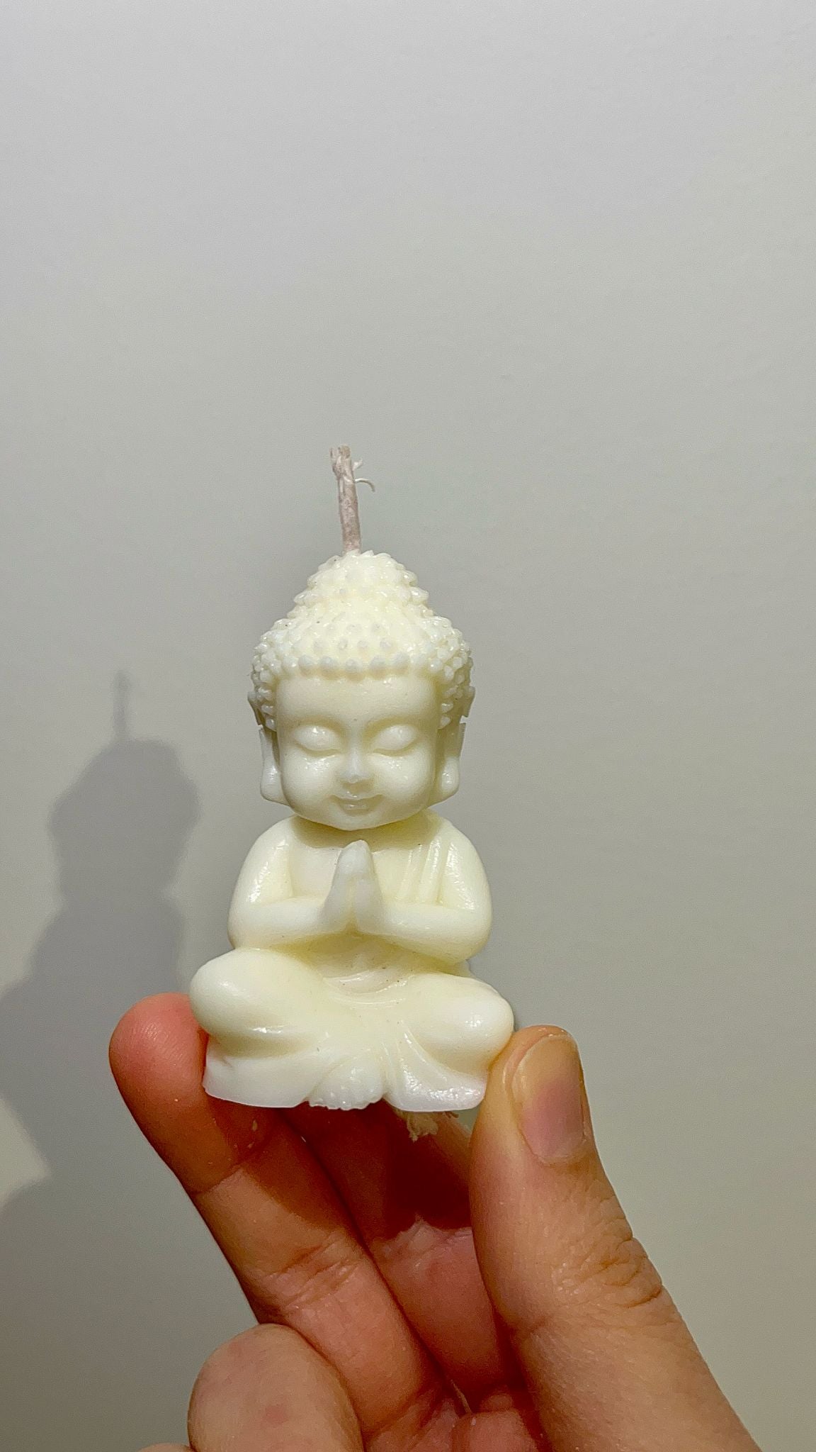 Vela Buda Zen sostenida en la mano, vista frontal mostrando detalles del rostro y postura serena del Buda