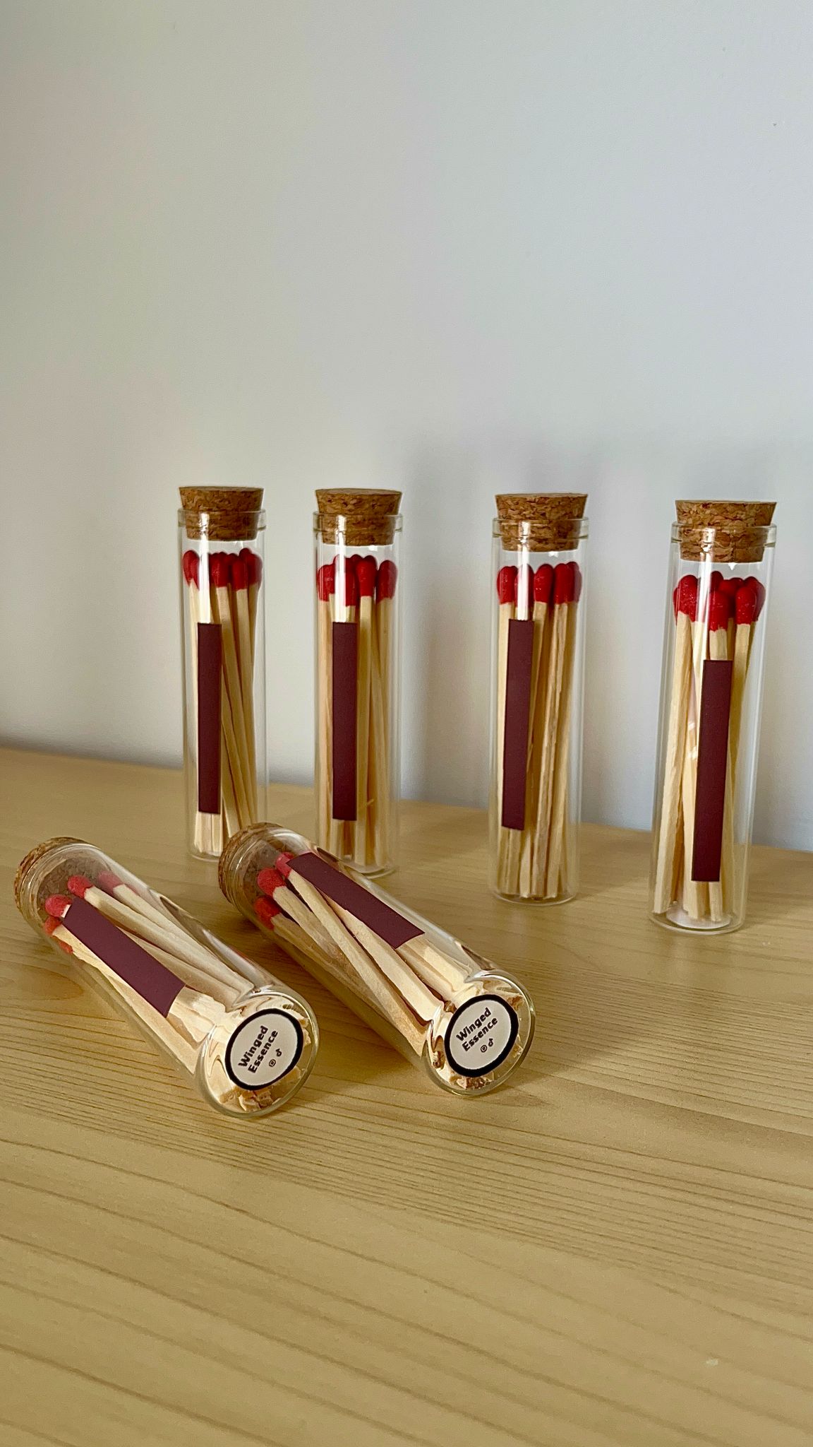 Cuatro porta fósforos de cristal con fósforos rojos, alineados de pie sobre una superficie de madera.