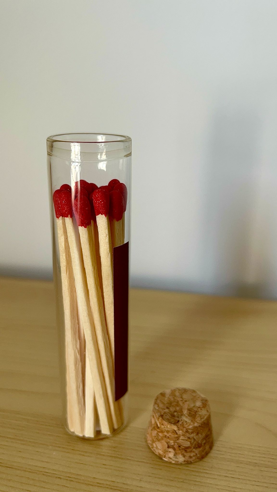 Porta fósforos de cristal de pie con tapón retirado, mostrando los fósforos rojos visibles en su interior