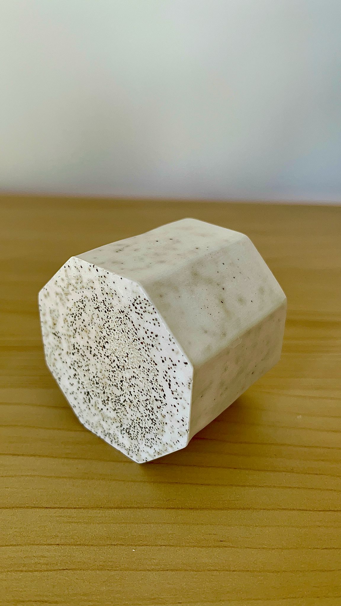 Vela Café París tumbada de lado para mostrar su base y forma hexagonal con acabado marmoleado