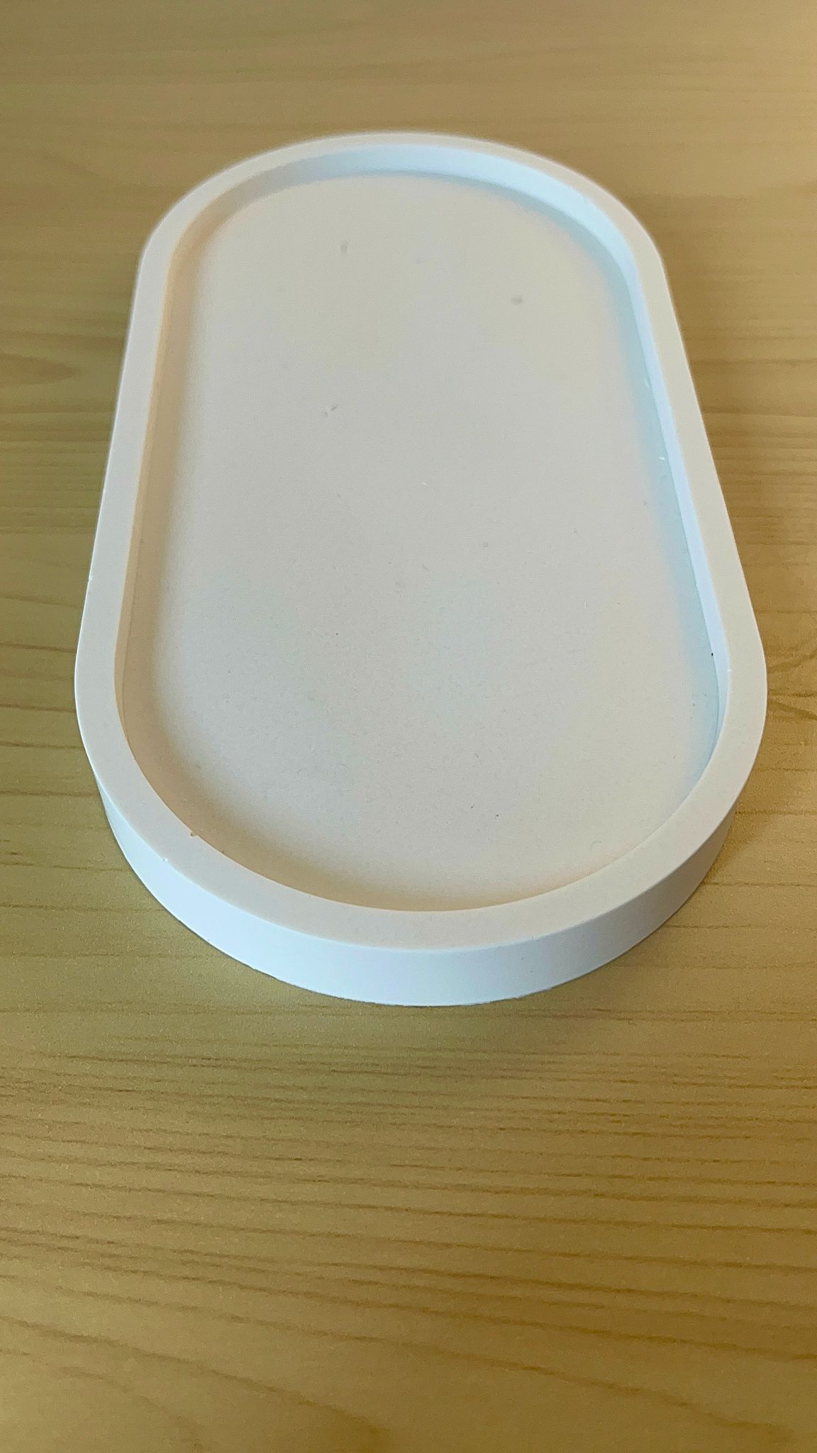 Vista desde arriba de frente, bandeja ovalada decorativa de acabado minimalista, elaborada a mano, parte de la colección de decoración de Winged Essence.