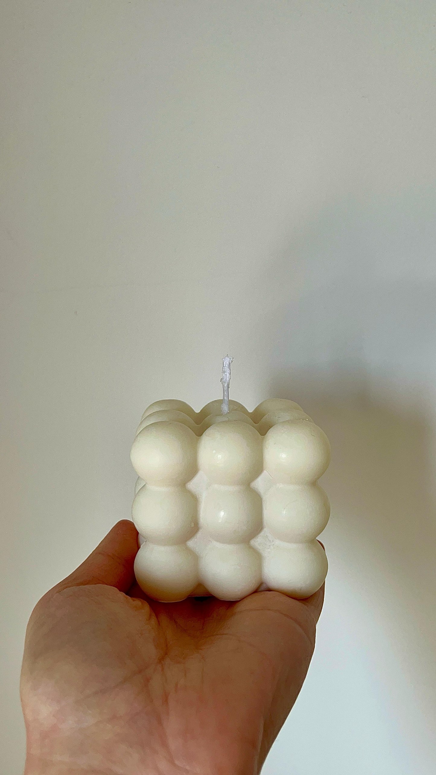 Vela cubo de burbujas maxi sostenida en la mano, vista frontal mostrando su volumen y diseño en forma de esferas agrupadas