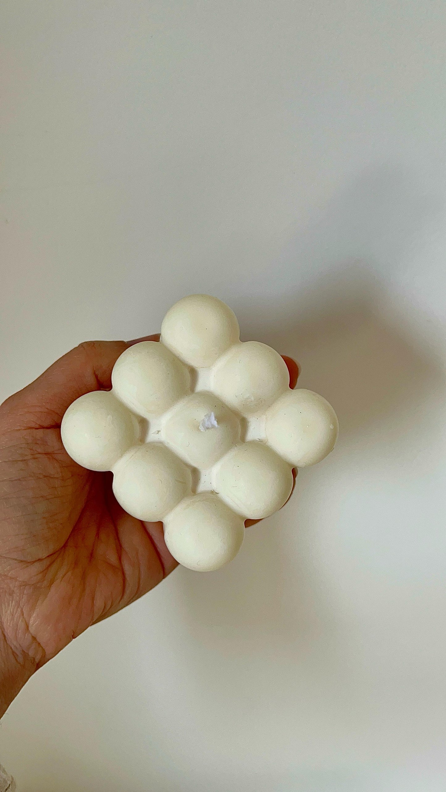Vela decorativa cubo de burbujas maxi sostenida en una mano, resaltando su tamaño generoso y forma geométrica
