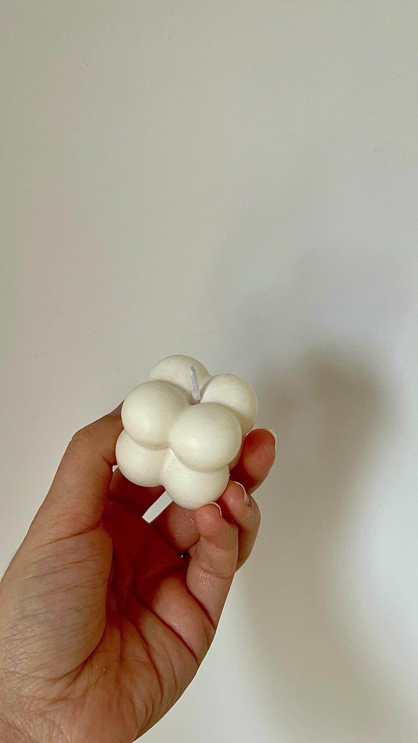 Vela cubo de burbujas mini sostenida en la mano desde un ángulo lateral, mostrando su tamaño compacto y diseño geométrico