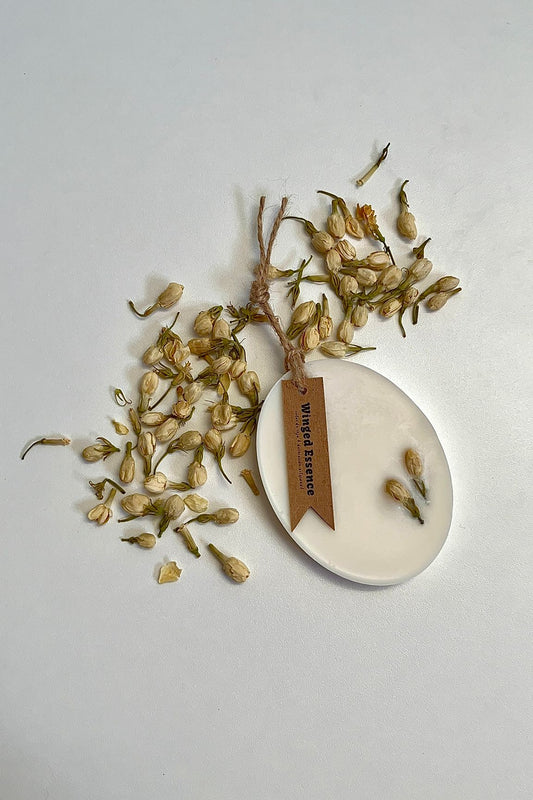 Ambientador para armario Gardenia Aloe Vera en forma ovalada con flores secas y etiqueta colgante. Elaborado con cera de soja natural y aceites esenciales.