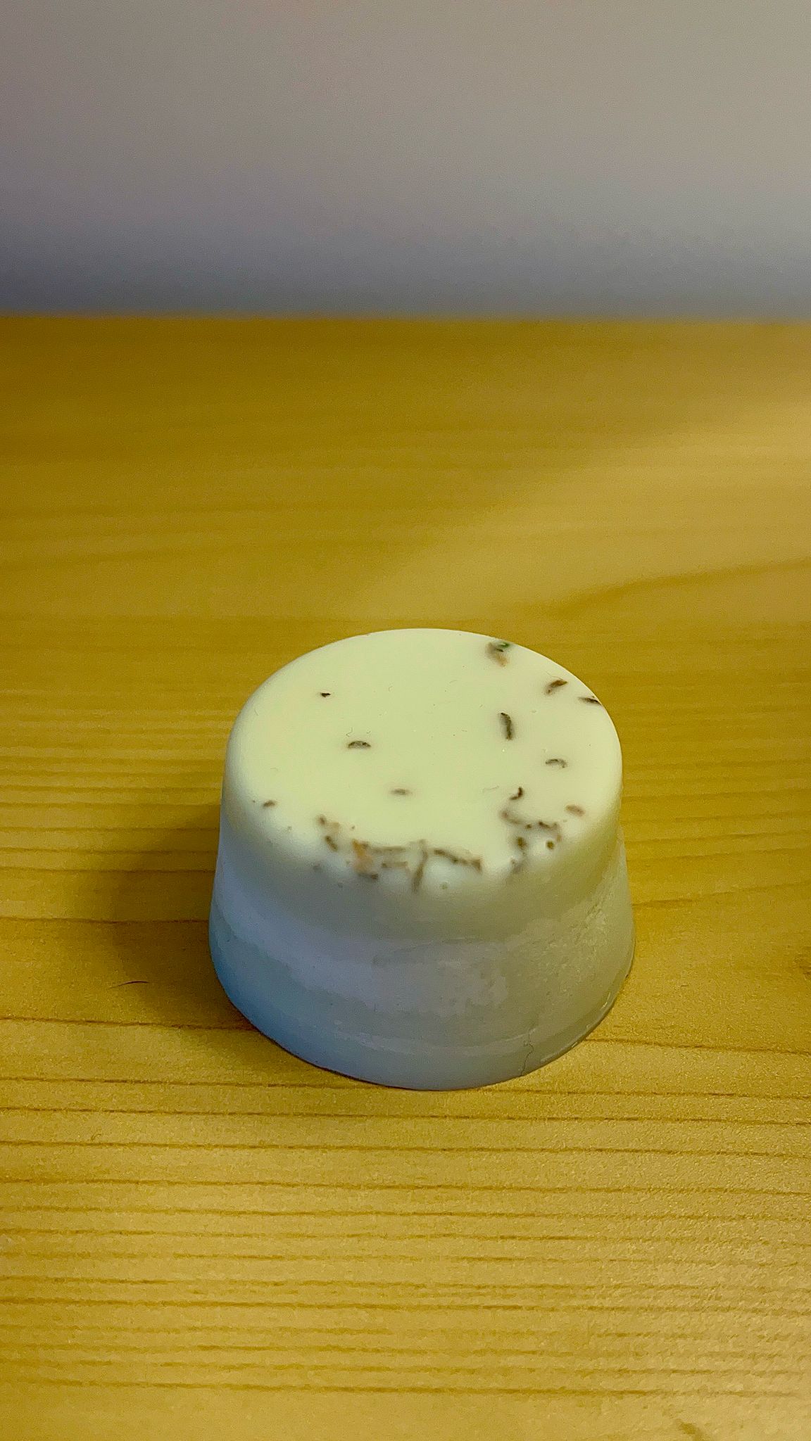 Melt de cera de soja color blanco con incrustaciones de flores secas visibles en la parte superior, colocado sobre madera